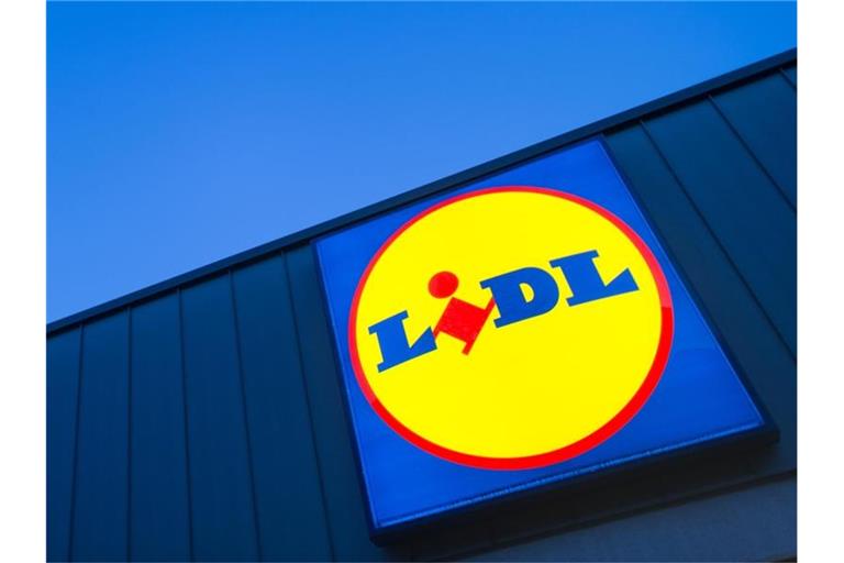 Das Logo eines Lidl-Supermarktes in Berlin-Reinickendorf leuchtet vor dem Abendhimmel. Foto: Matthias Balk/Archivbild