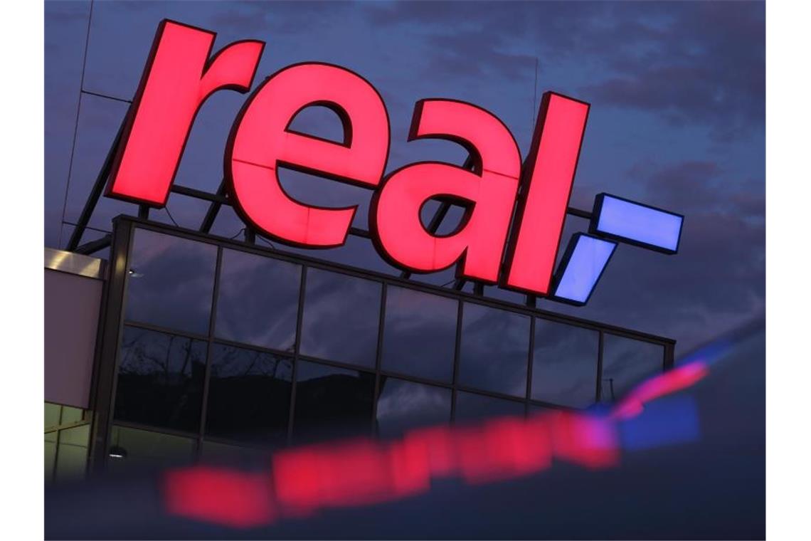 Das Logo leuchtet am Morgen auf dem Dach eines Real Supermarktes. Foto: Oliver Berg/dpa/Archiv