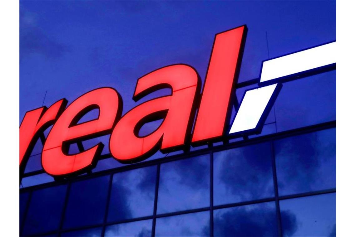 Kartellamt nimmt Verkauf von Real-Filialen unter die Lupe Das Logo leuchtet am Morgen auf dem Dach eines Real Warenhauses. Foto: Oliver Berg/dpa