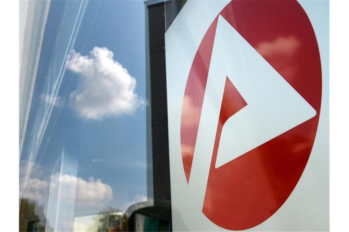 Arbeitslosenzahl im Südwesten nimmt etwas zu Das Logo vom Jobcenter spiegelt sich in einer Fensterscheibe während eine weiße Wolke am blauen Himmel zu sehen ist. Foto: Jens Kalaene/Archiv