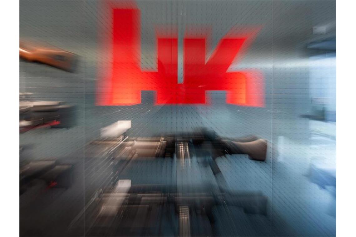 Schärfere Strafen für illegalen Waffenexport gefordert Das Logo von Heckler & Koch auf dem Firmengelände an einer Waffen-Präsentationswand. Foto: Marijan Murat/dpa/Archivbild