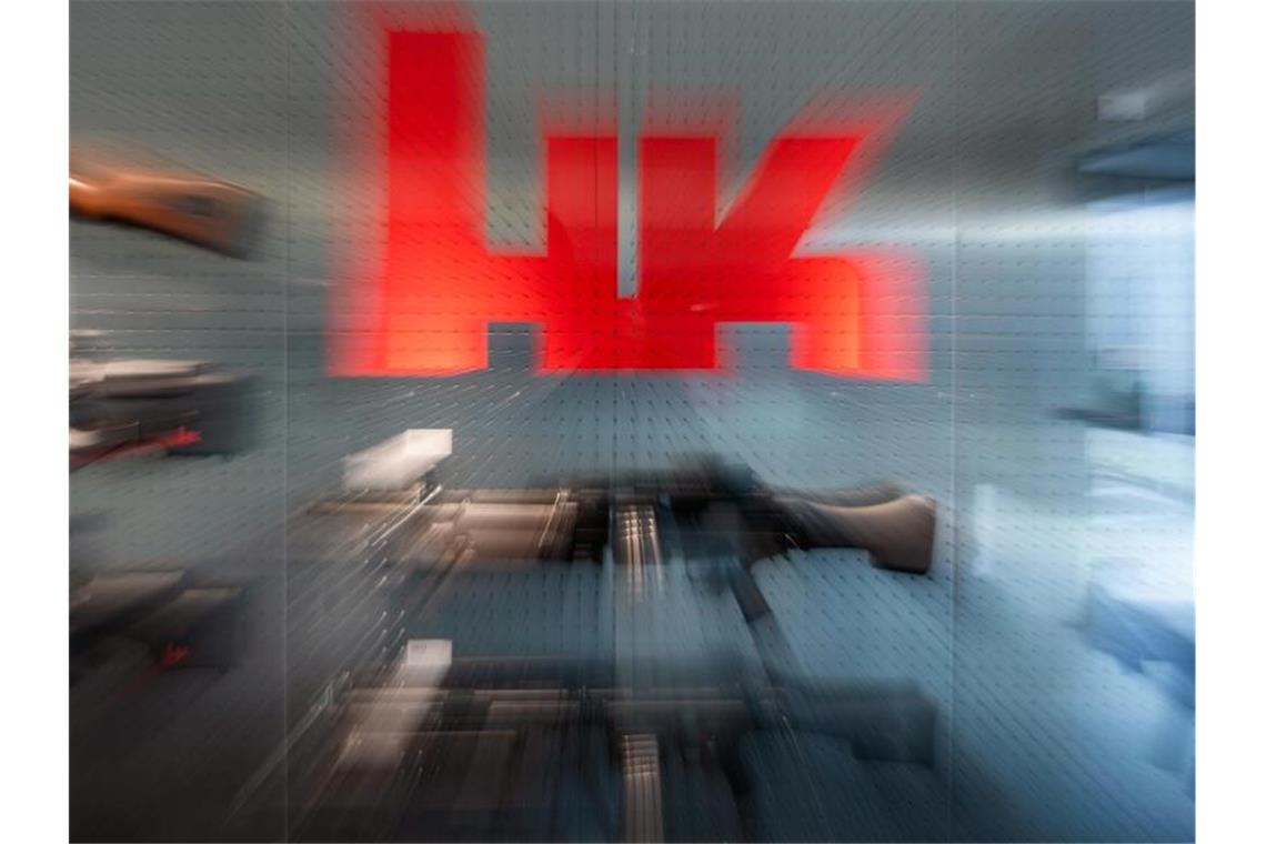 Das Logo von Heckler & Koch ist auf dem Firmengelände an einer Präsentationswand neben Waffen zu sehen. Foto: Marijan Murat/dpa/Symbolbild