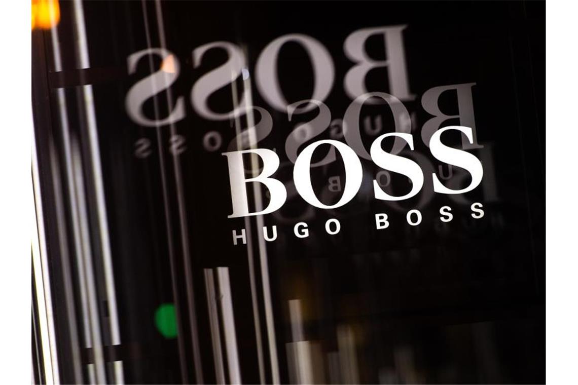 Das Logo von Hugo Boss spiegelt sich auf dem Kuhdamm in Berlin in mehreren Glasscheiben. Foto: Sebastian Gollnow/dpa/Archivbild