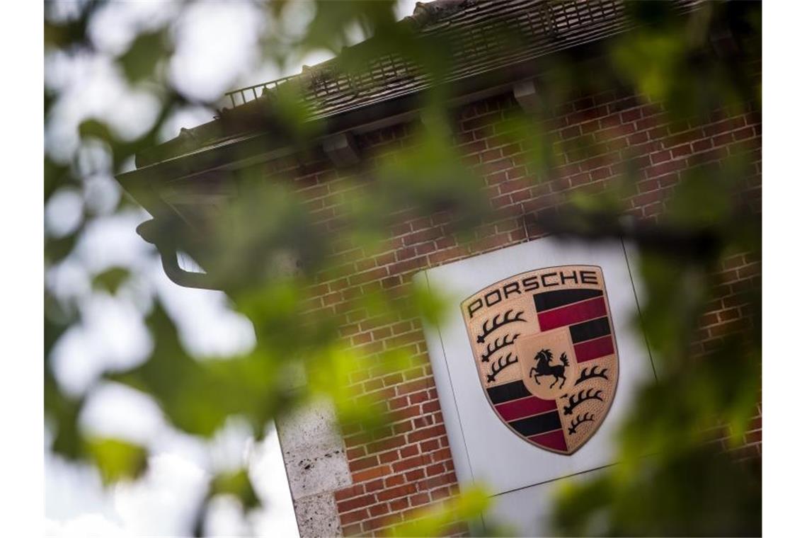 Ermittlungen gegen Porsche liegen erst einmal auf Eis Das Logo von Porsche ist durch ein Geäst zu sehen. Foto: Christoph Schmidt/Archivbild