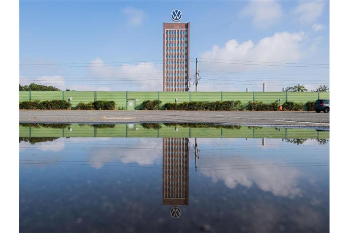 Das Markenhochhaus vom Volkswagen spiegelt sich in einer Pfütze auf einem Mitarbeiterparkplatz vor dem VW Werk Wolfsburg. (Archivbild). Foto: Julian Stratenschulte/dpa