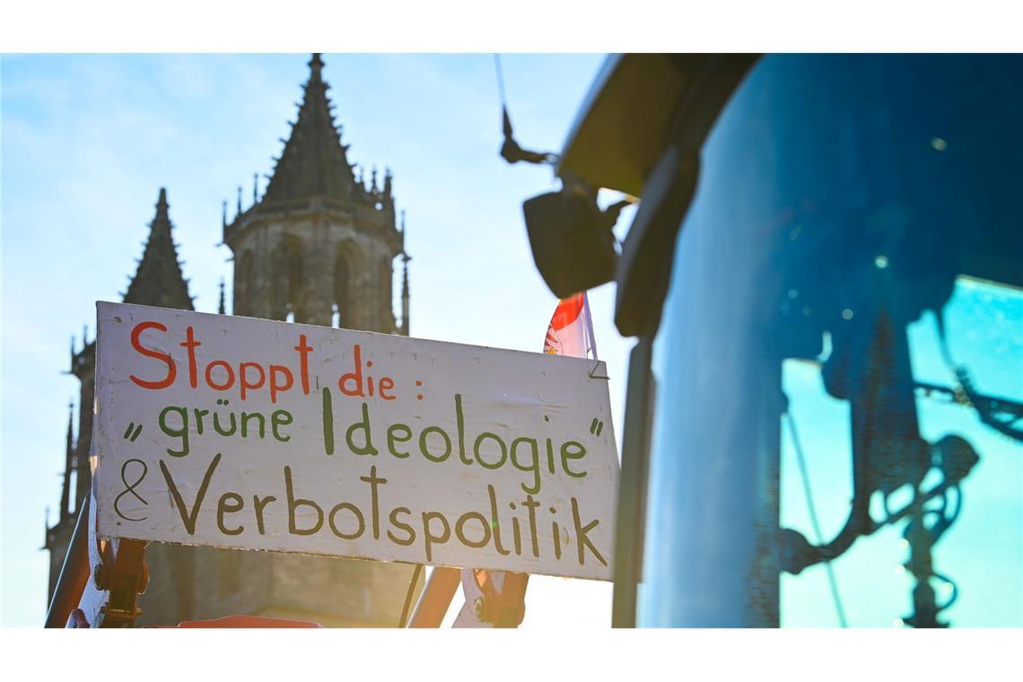 Das Motto lautet "Zu viel ist zu viel": Ein Protestplakat mit der Aufschrift "Stoppt die grüne Ideologie und Verbotspolitik" ist an einem Traktor vor dem Dom in Magdeburg befestigt.