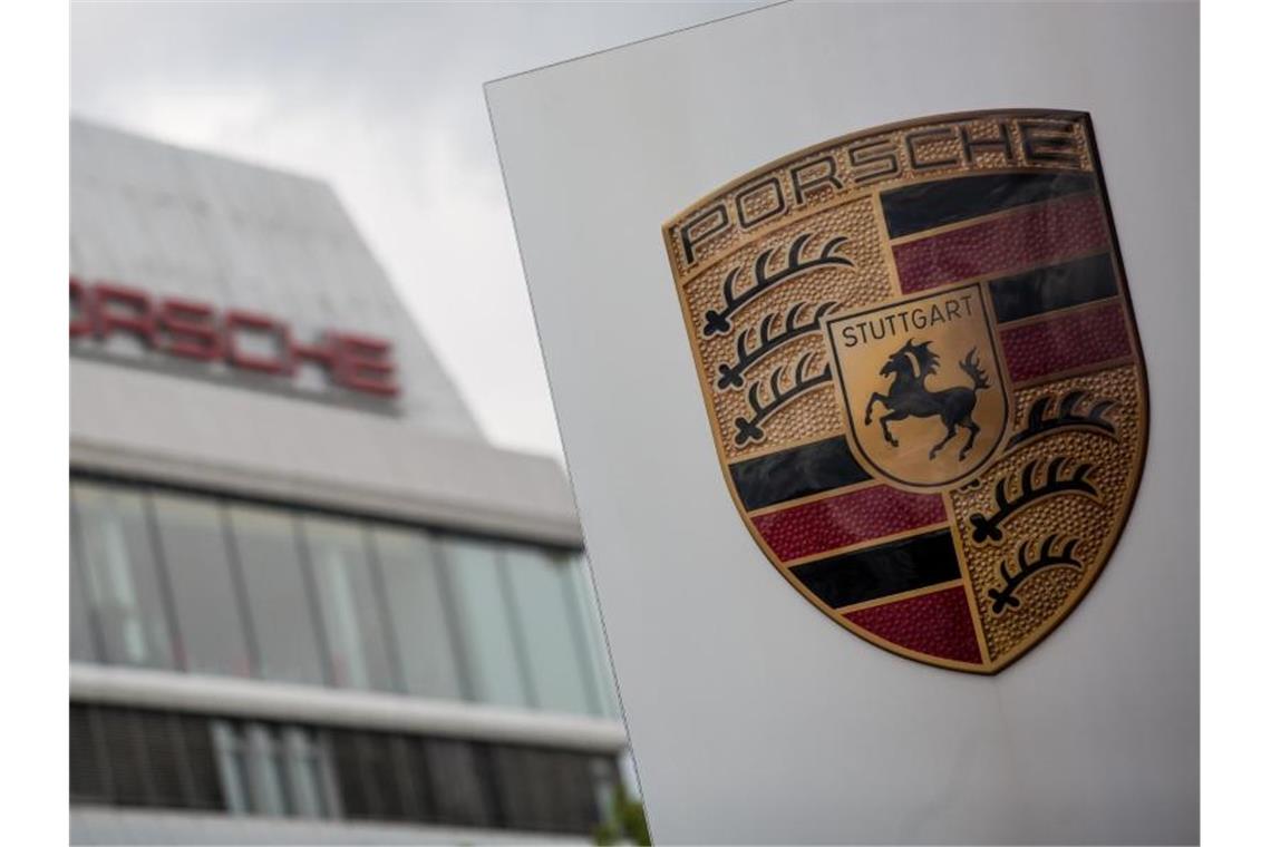 Das Porsche Logo ist vor einem Gebäude des Automobilherstellers zu sehen. Foto: Christoph Schmidt/Archivbild