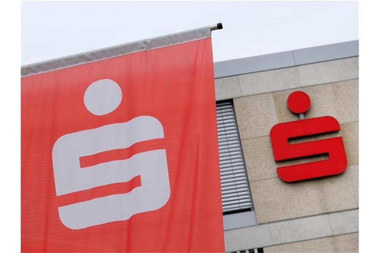 Das Sparkassenlogo ist auf einer Fahne und an einem Gebäude der Sparkasse angebracht. Foto: Bernd Weissbrod/dpa/Symbolbild