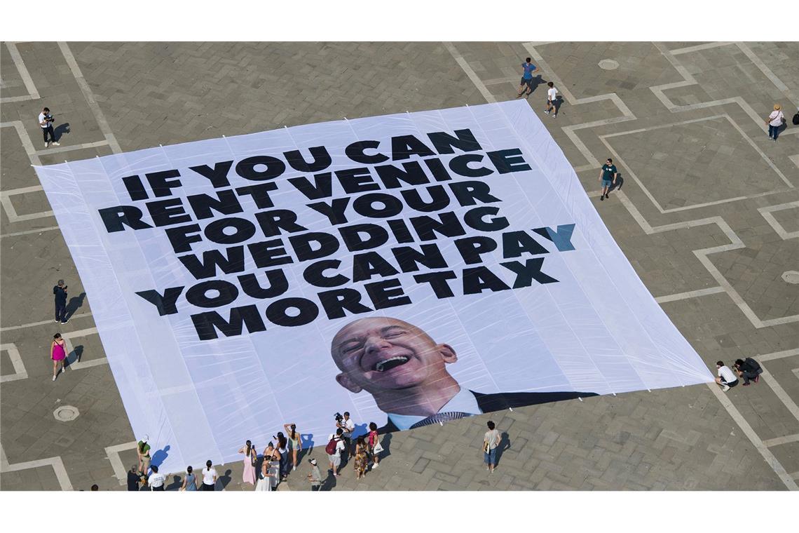 Krieg bringt Hochzeitspläne von Bezos durcheinander Das Transparent zeigt ein Foto des Amazon-Gründers, auf dem steht: "If you can rent Venice for your wedding you can pay more tax".
