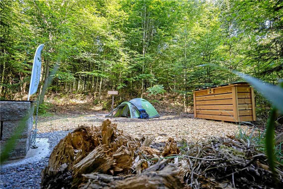 Das Trekkingcamp liegt mitten im Wald. Das Zelt lässt sich auf mit Holzhackschnitzeln präparierten Plätzen aufschlagen. Den Grill (links) und das Holzlager (rechts) darf man wegen der Waldbrandgefahr aber zurzeit nicht nutzen.