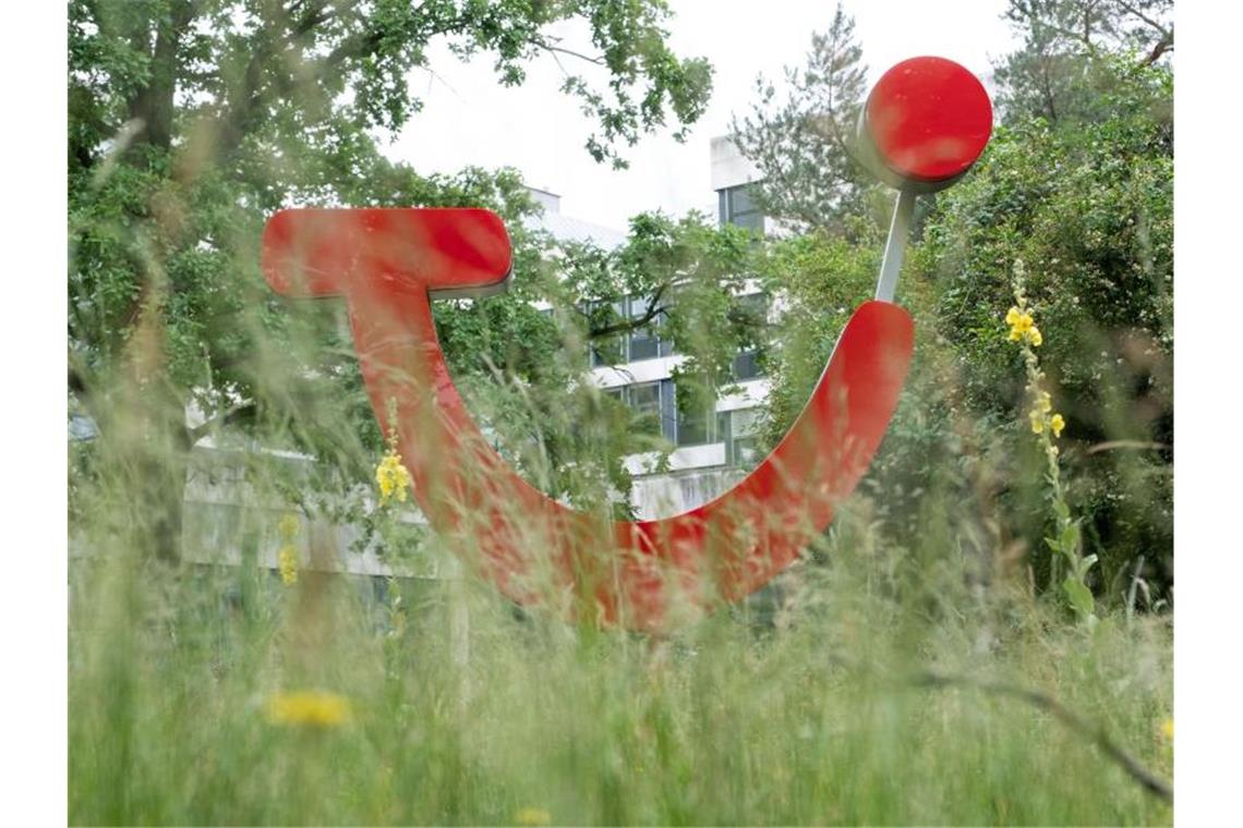 Das Tui-Logo hinter hohem Gras vor der Firmenzentrale in Hannover. Foto: Peter Steffen/dpa/Symbolbild