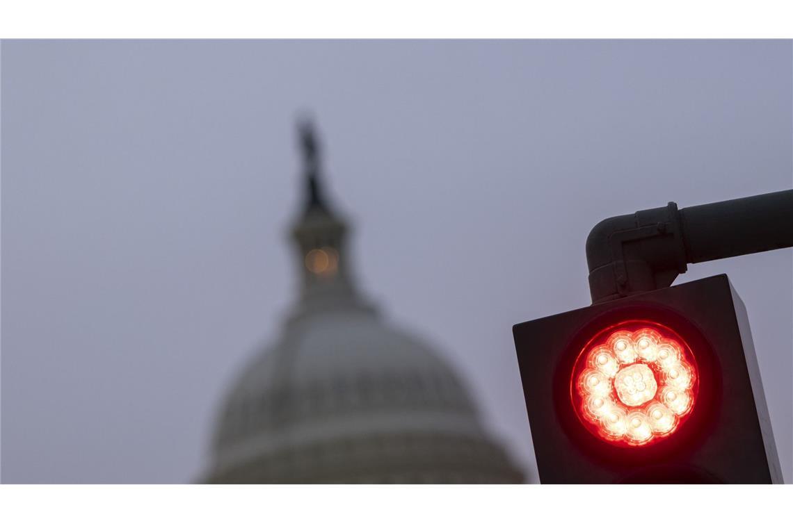 Das US-Kapitol steht in Washington ist hinter einer roten Ampel zu sehen. Nach Ablauf der Frist für einen Übergangshaushalt stehen die Regierungsgeschäfte in den USA teilweise still.