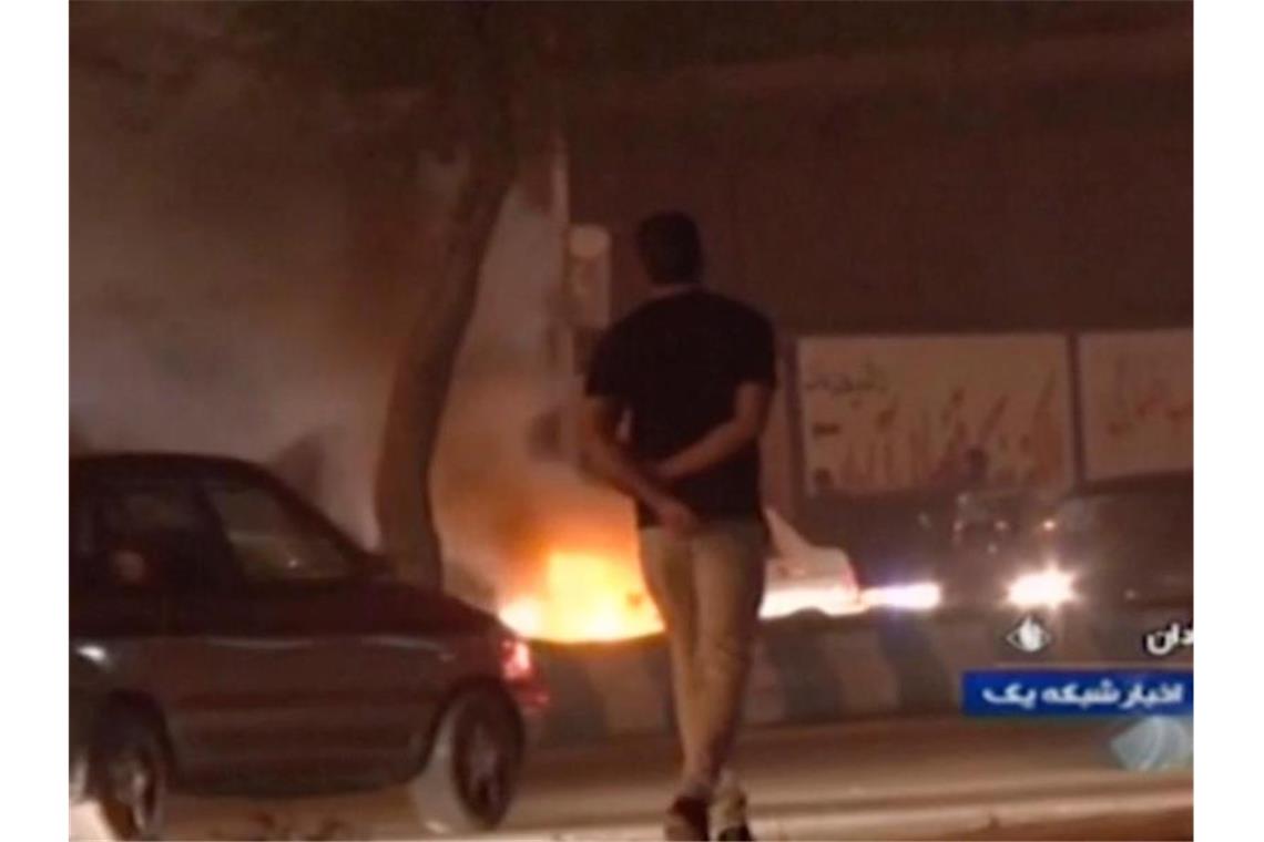 Das Videostandbild, das die staatliche Rundfunkgesellschaft der Islamischen Republik Iran zur Verfügung gestellt hat, geht ein Mann an einem Feuer vorbei, das von Demonstranten in Abadan gelegt wurde. Foto: Islamic Republic of Iran Broadcasting/AP/dpa