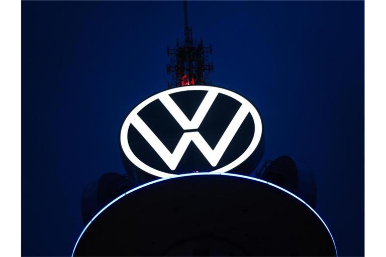 Das Volkswagen Logo leuchtet auf dem VW-Tower vor dunklem Himmel. Foto: Ole Spata/dpa