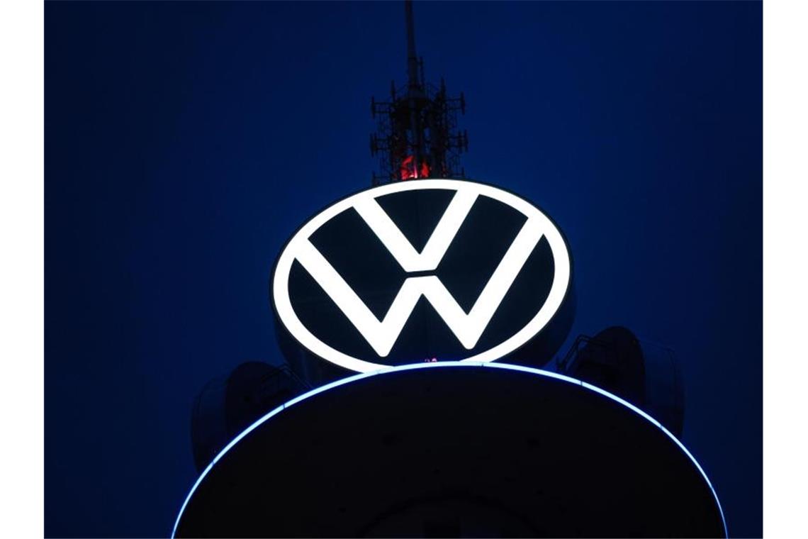Das Volkswagen Logo leuchtet auf dem VW-Tower vor dunklem Himmel. Foto: Ole Spata/dpa