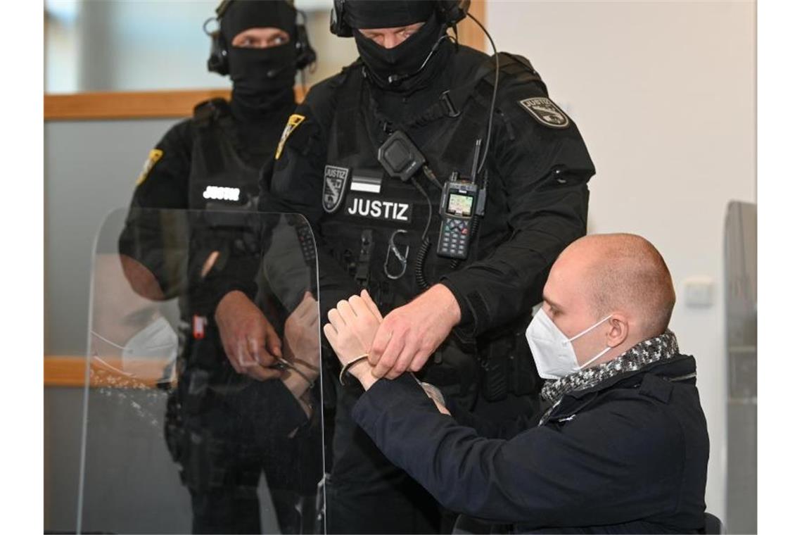 Dem angeklagten Stephan Balliet werden zu Beginn des 24. Prozesstages am 8. Dezember im Saal des Landgerichts die Handfesseln abgenommen. Foto: Hendrik Schmidt/dpa-Zentralbild/dpa