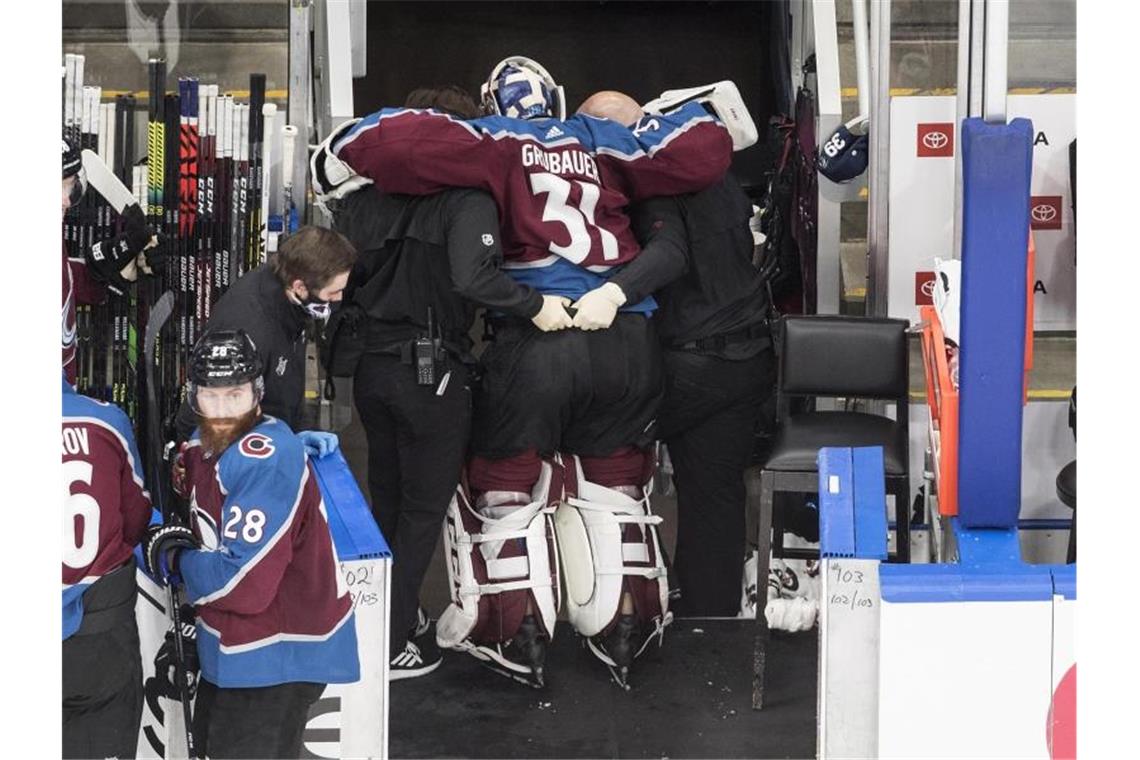 Dem verletzten Torhüter Philipp Grubauer (M) von den Colorado Avalanche wird in die Umkleidekabine geholfen. Foto: Jason Franson/The Canadian Press/AP/dpa