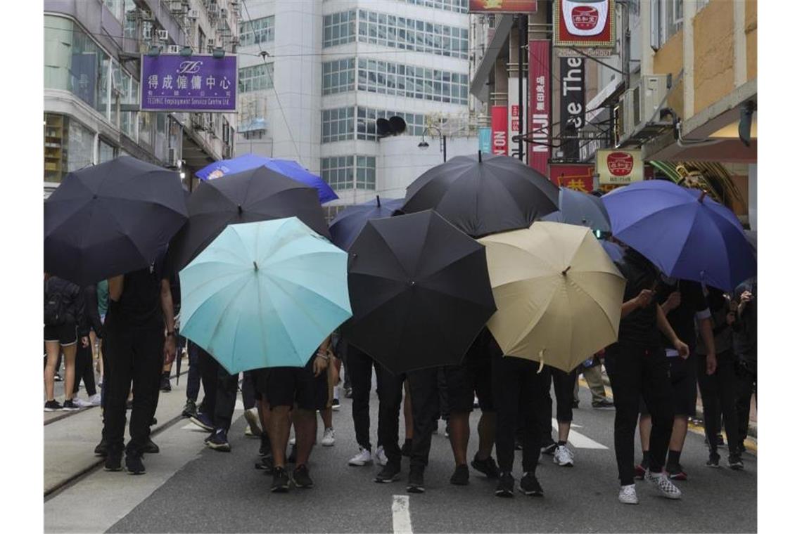 Demonstranten bilden ein Schutzschild aus Regenschirmen. Foto: Vincent Yu/AP/dpa