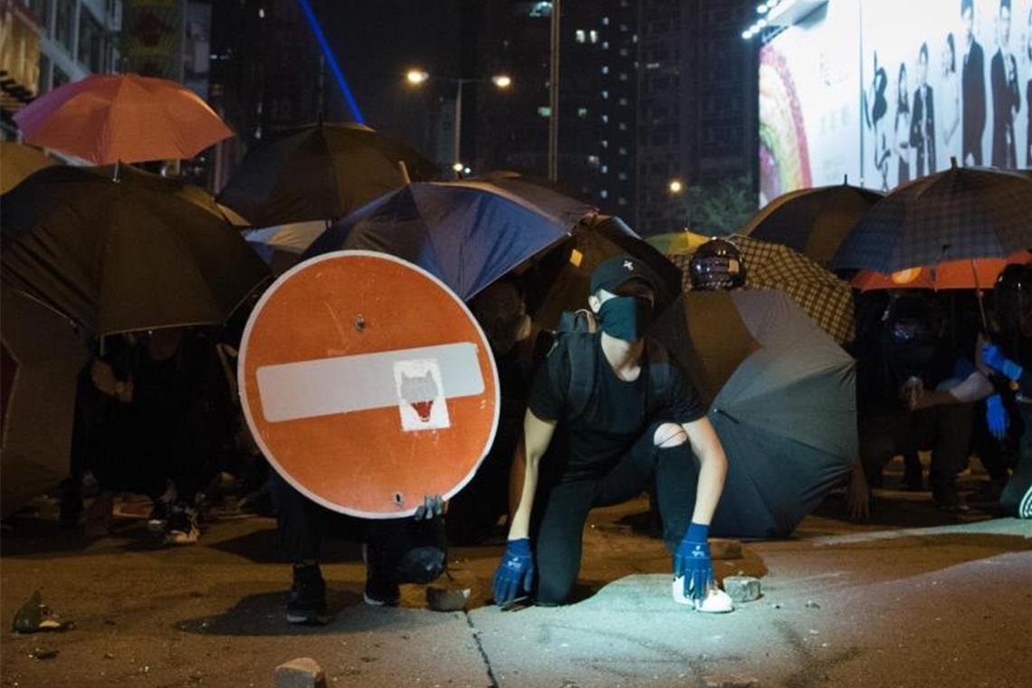 Demonstranten bilden hinter Regenschirmen gegen die Polizei eine Barrikade. Foto: Oliver Haynes/SOPA Images via ZUMA Wire/dpa