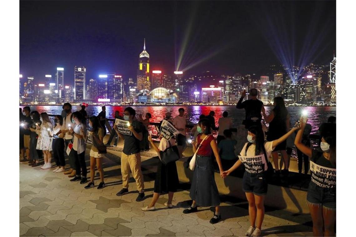 Neue Zusammenstöße in Hongkong - Wasserwerfer auf der Straße Demonstranten bilden in Hongkong eine Menschenkette. Foto: Vincent Yu/AP