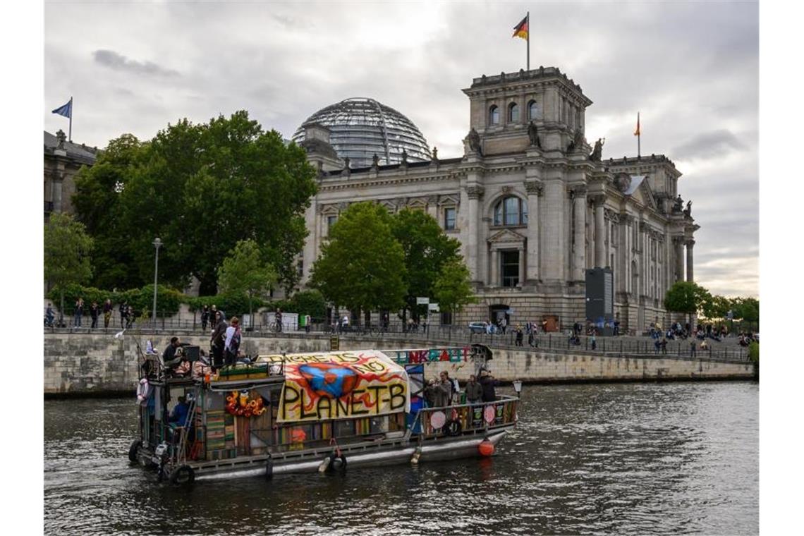 Demonstranten fahren mit einem Boot am Berliner Reichstagsgebäude vorbei. Das Klimapaket der Bundesregierung wird von Opposition, Umweltschützern und Wirtschaftsverbänden weiter scharf kritisiert. Foto: Christophe Gateau