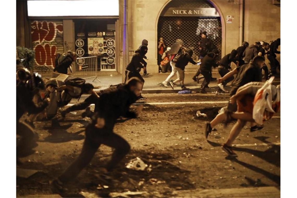 Demonstranten fliehen vor Polizisten. Foto: Emilio Morenatti/AP/dpa