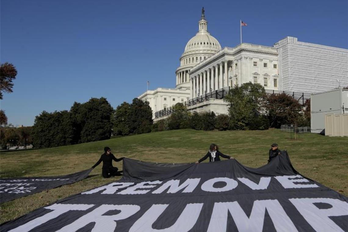 Demonstranten fordern mit einem Banner vor dem Kapitol das politische Ende von US-Präsident Trump. Foto: Julio Cortez/AP/dpa