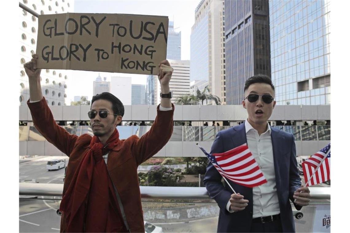 Demonstranten halten amerikanische Flaggen und ein Plakat mit der Aufschrift „Glory to USA, Glory to Hong Kong“ („Ruhm für die USA, Ruhm für Hong Kong“) hoch. Foto: Kin Cheung/AP/dpa