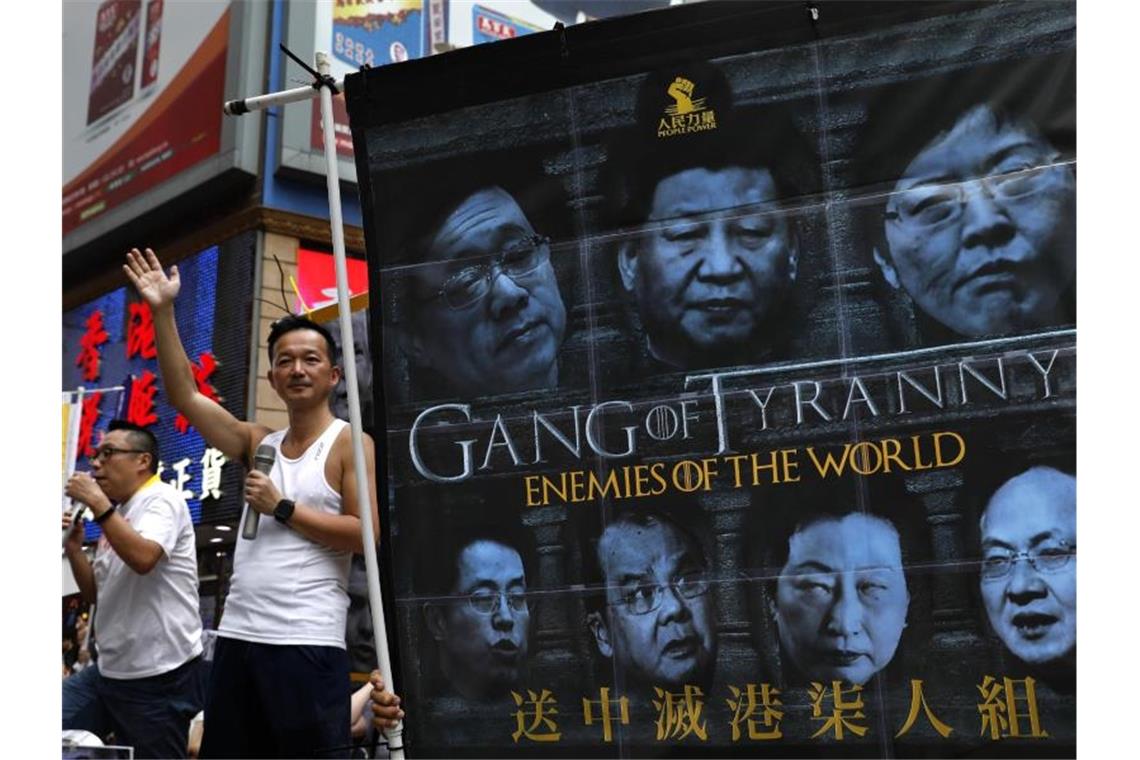 Demonstranten halten ein Banner, auf dem unter anderem der chinesische Präsident Xi (M) zu sehen ist, mit der Aufschrift „Game of Tyranny - Enemies of the World“. Foto: Vincent Yu/AP
