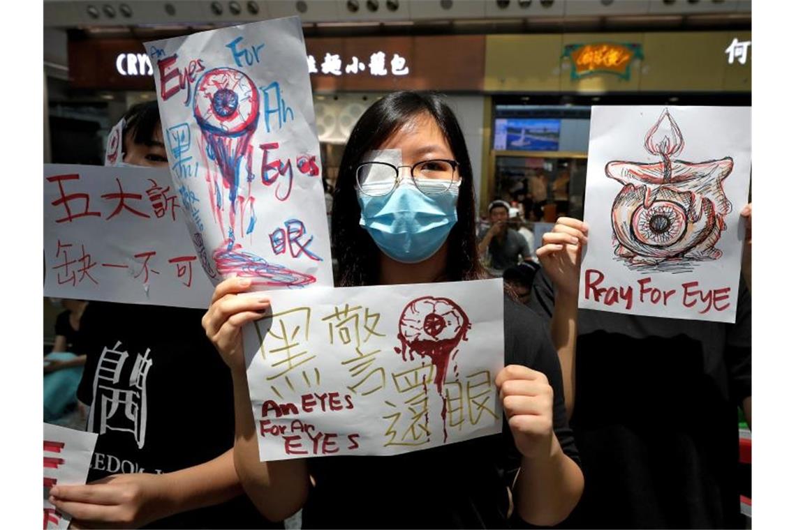 Heftige Zusammenstöße in Hongkongs Flughafen Demonstranten halten in der Ankunftshalle des Flughafens Schilder hoch. Mit dem Airport von Hongkong hat einer der verkehrsreichsten Flughäfen der Welt ein zweites Mal innerhalb von zwei Tagen den Betrieb eingestellt. Foto: Vincent Thian/AP