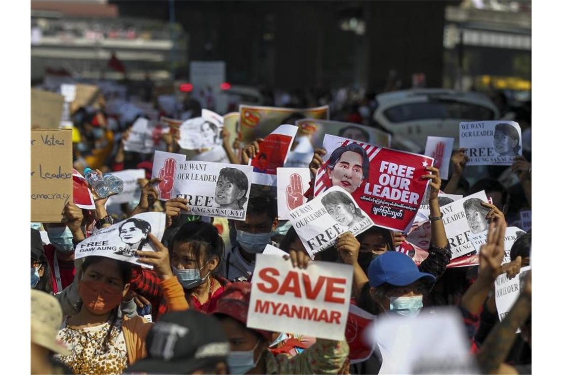 Demonstranten halten in Rangun Plakate hoch, die die Freilassung der inhaftierten myanmarischen Regierungschefin Aung San Suu Kyi fordern. Foto: Str/AP/dpa
