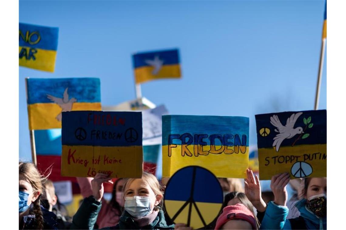 Solidarität: Glockengeläut und große Demonstrationen Demonstranten halten Schilder mit den Farben der ukrainischen Flagge in die Luft. Die Organisation Fridays for Future geht an diesem Donnerstag weltweit auf die Straße, um ihre Solidarität mit der Ukraine zu bekunden und um gegen den Angriff Russlands auf das Land zu protestieren. Foto: Fabian Strauch/dpa