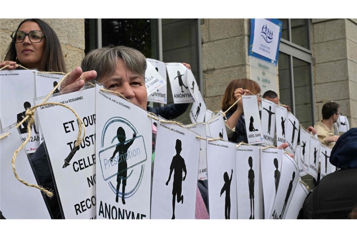 299-facher Missbrauch: 20 Jahre Haft für Arzt in Frankreich Demonstranten halten vor dem Gerichtsgebäude Schilder mit den Namen der Opfer.