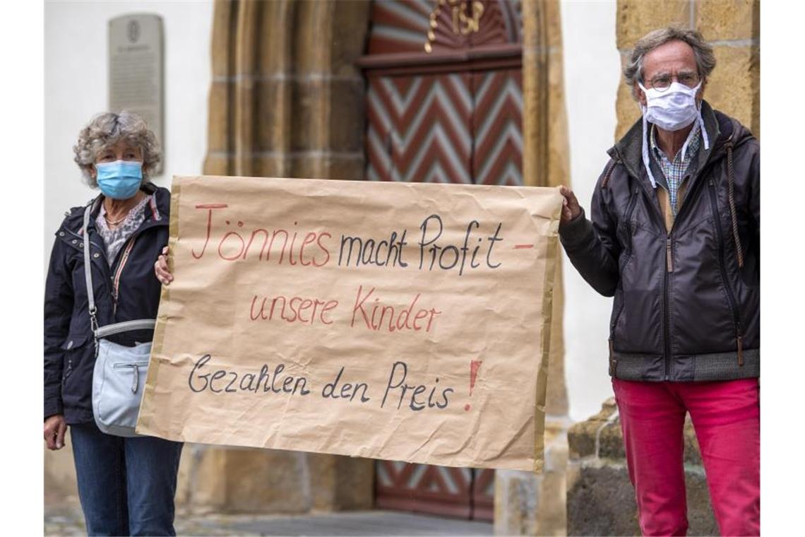 Demonstranten halten während einer Mahnwache zur Situation beim Fleischwerk Tönnies auf dem Marktplatz in Rheda-Wiedenbrück ein Schild mit der Aufschrift „Tönnies macht Profit - unsere Kinder bezahlen den Preis!“. Foto: David Inderlied/dpa