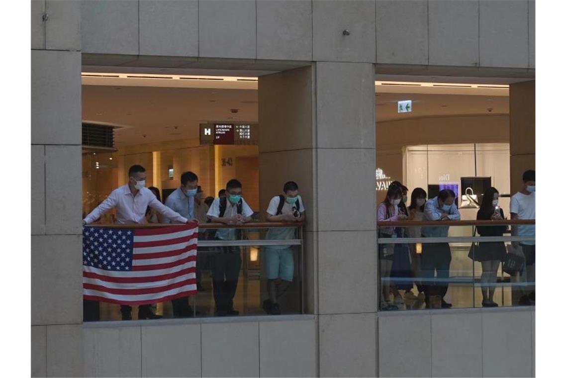 USA wollen Hongkong Vorteile streichen - China protestiert Demonstranten in einem Hongkonger Einkaufszentrum zeigen eine US-Flagge. Foto: Vincent Yu/AP/dpa