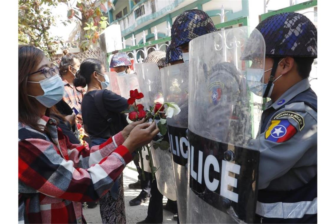 Mit Symbolen gegen den Putsch in Myanmar Demonstranten in Mandaley überreichen der Polizei Rosen, während vier festgenommene Aktivisten vor Gericht erscheinen. Foto: Uncredited/AP/dpa