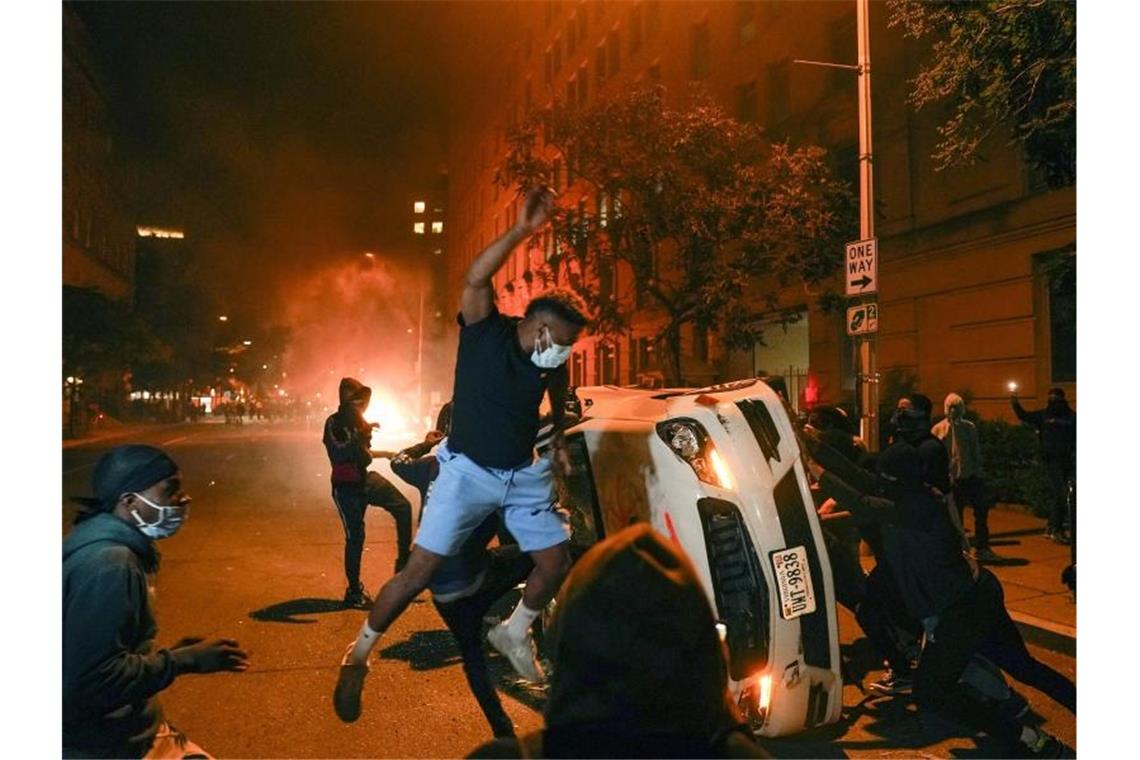 Demonstranten in Washington kippen ein parkendes Auto um und zertrümmern die Scheiben. Foto: Evan Vucci/AP/dpa