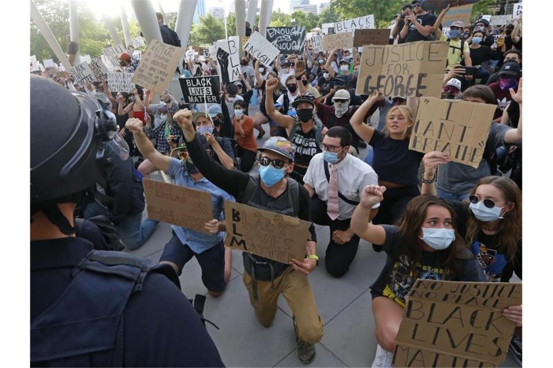 Demonstranten knien bei einem Protest vor einem Polizisten nieder. Foto: Rick Bowmer/AP/dpa