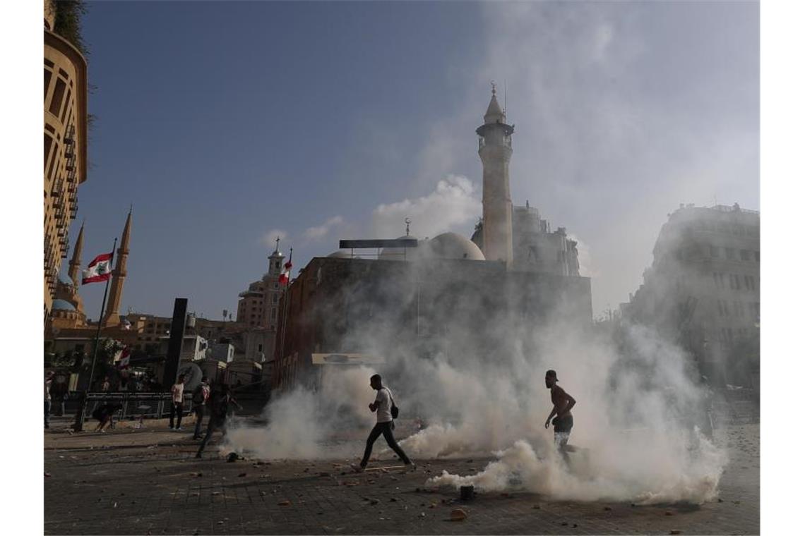 Demonstranten laufen auf dem Märtyrer-Platz durch Tränengas. Foto: Hassan Ammar/AP/dpa