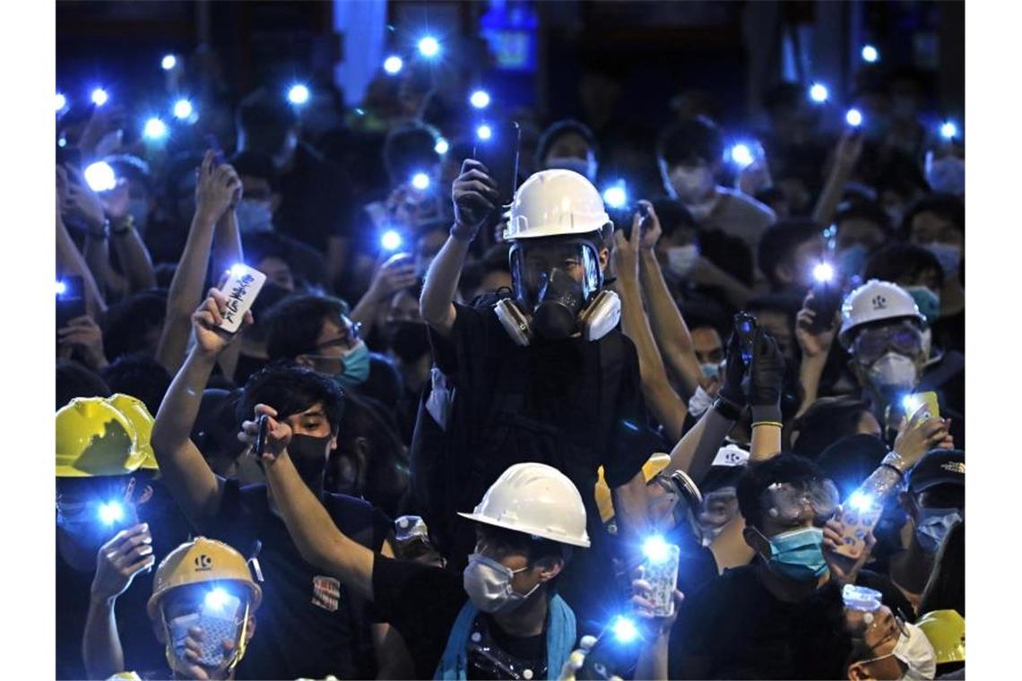 Proteste gegen Hongkonger Regierung flammen wieder auf Demonstranten leuchten mit dem Licht ihre Handys vor dem Polizeipräsidium von Hongkong. Foto: Vincent Yu/AP