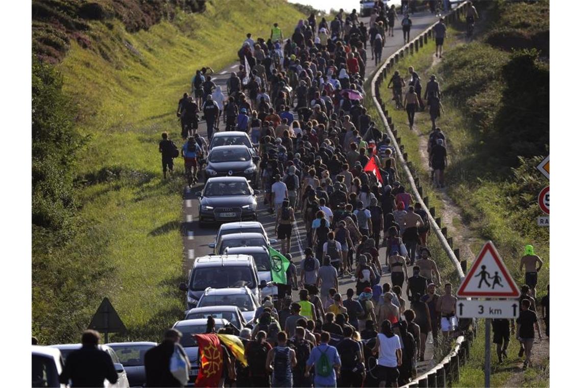 Demonstranten marschieren auf einer Straße in der Nähe eines Zeltlagers während eines Protest gegen den G7-Gipfel. Foto: Emilio Morenatti/AP