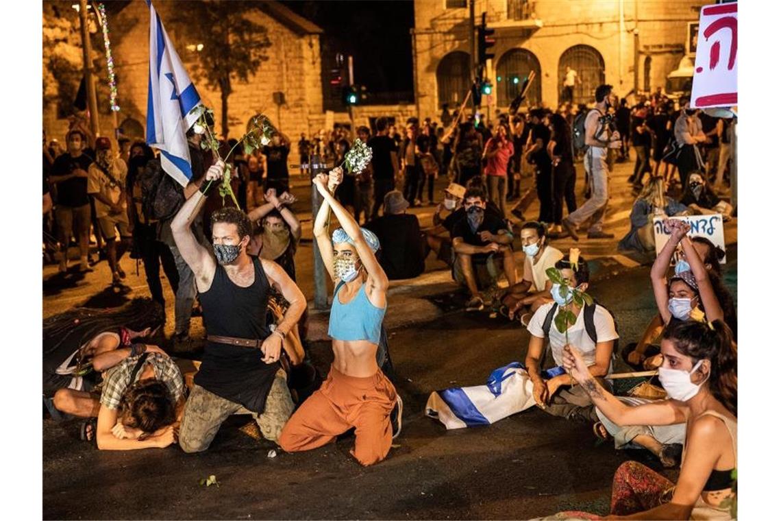 Demonstranten protestieren gegen den israelischen Ministerpräsidenten Netanjahu in der Nähe seiner Residenz. Foto: Ilia Yefimovich/dpa