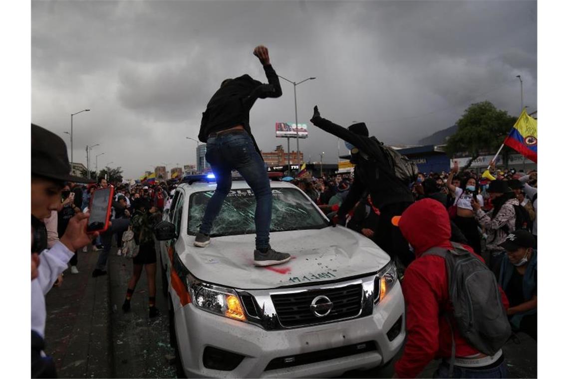 Demonstranten schlagen während des Protests in Bogota auf einen Polizeiwagen ein. Foto: Camila Diaz/colprensa/dpa