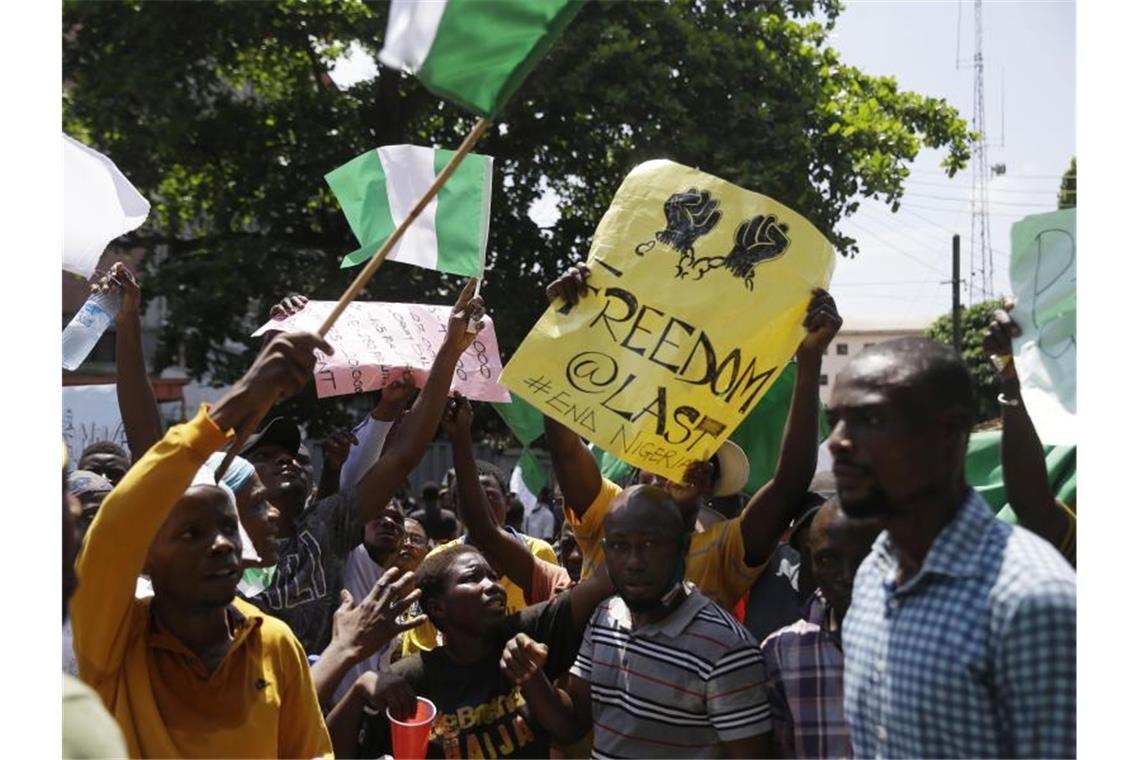 Lagos: Weltweites Entsetzen nach Schüssen auf Demonstranten Demonstranten schwenken bei einem Protest gegen Polizeigewalt die nigerianische Fahne und halten Transparente. Foto: Sunday Alamba/AP/dpa