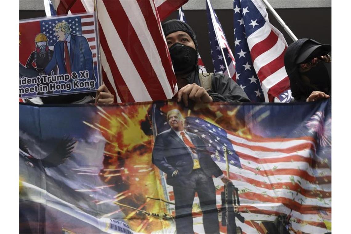 Hongkongs Polizei stoppt Marsch von Zehntausenden mit Gewalt Demonstranten schwenken in Hongkong US-Fahnen und Plakate. Foto: Ng Han Guan/AP/dpa