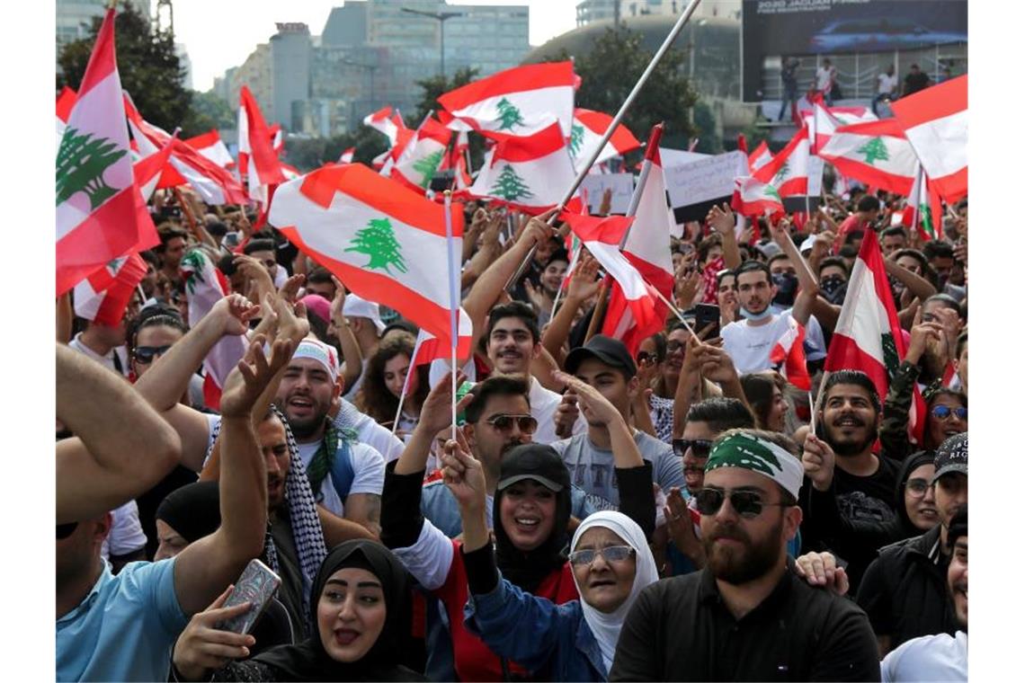 Demonstranten schwenken libanesische Flaggen und fordern wegen der schweren Wirtschaftskrise im Land einen Regierungswechsel. Foto: Marwan Naamani/dpa