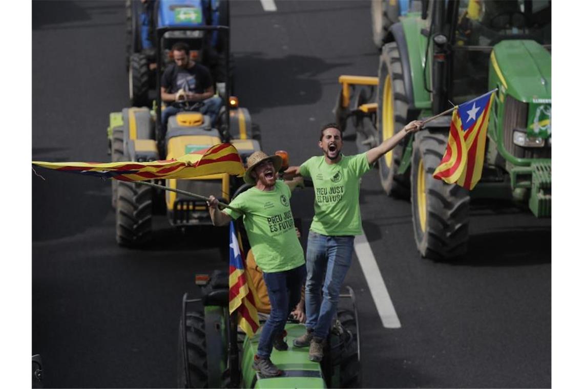 Demonstranten stehen auf einem Traktor und schwenken katalanische Fahnen. Foto: Manu Fernandez/AP/dpa