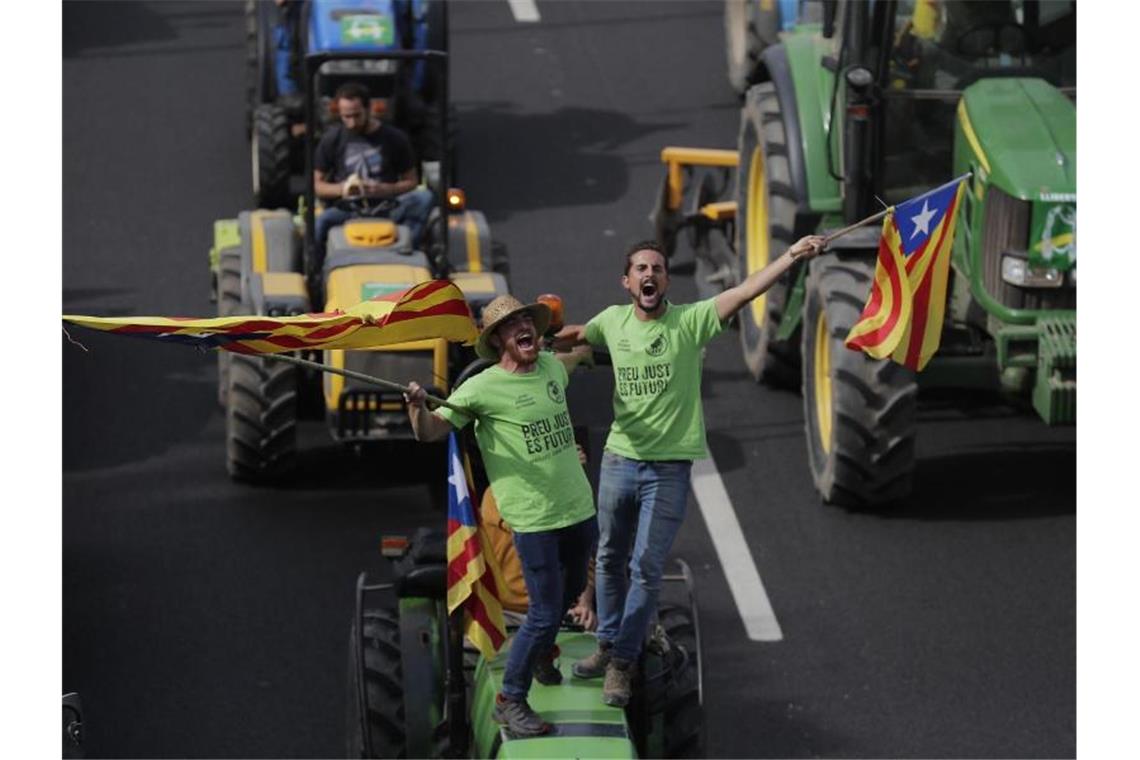 Nach neuer Krawallnacht in Katalonien: Madrid erhöht Druck Demonstranten stehen auf einem Traktor und schwenken katalanische Fahnen. Foto: Manu Fernandez/AP/dpa