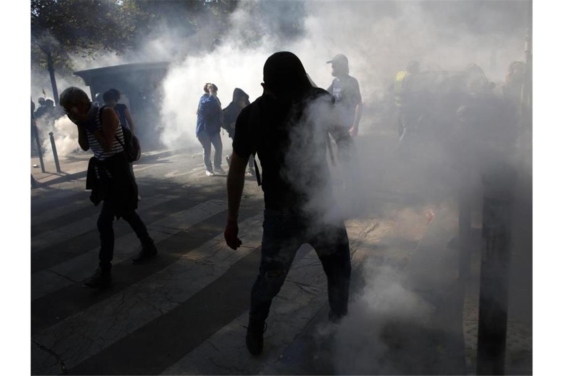 Demonstranten stehen in Paris im Tränengasnebel. Foto: Thibault Camus/AP