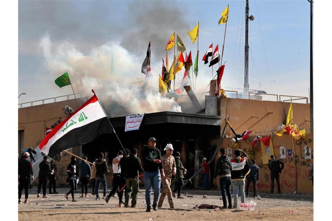 Demonstranten stehen mit Fahnen vor der US-Botschaft in Bagdad. Foto: Khalid Mohammed/AP/dpa